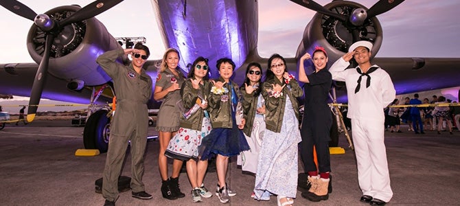 Nu Skin Sales Leaders pose in front of airplane on Ford Island dressed in military themed attire.